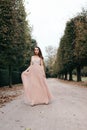 Beautiful woman in long rose evening dress walking path in park. Royalty Free Stock Photo