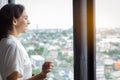 Beautiful woman look at nice view of cityscape at condominium room or hotel of hig building. Gorgeous woman wear bathrobe. Pretty Royalty Free Stock Photo