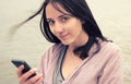 Beautiful woman looking at camera in european city using her smartphone water of river on background