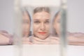 Beautiful woman looking through glass water looks into camera, bright orange Royalty Free Stock Photo