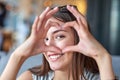 Beautiful woman looking through heart gesture made with hands