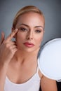 Beautiful woman looking her wrinkles in mirror Royalty Free Stock Photo