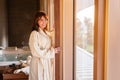 Beautiful woman is looking out from window while waiting for massage at spa center. Royalty Free Stock Photo