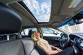 The beautiful woman looks at the blue sky through wet glass of a roof of the car Royalty Free Stock Photo