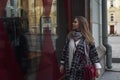 Beautiful woman looks at a shop window. Young blonde in a stylish coat and with a red bag. Style and fashion Royalty Free Stock Photo