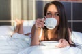 Beautiful woman lying in bed and drinking coffee or tea the morning Royalty Free Stock Photo