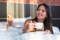 Beautiful woman lying in bed and drinking coffee or tea the morning Royalty Free Stock Photo