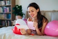 Beautiful woman lying on bed in the middle of baloons, reading love letter. Concept of Valentine& x27;s Day, love and Royalty Free Stock Photo