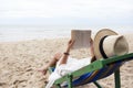 A woman lying down and reading book on the beach chair with feeling relaxed Royalty Free Stock Photo