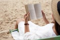 A woman lying down and reading book on the beach chair with feeling relaxed Royalty Free Stock Photo