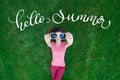 Beautiful woman lying on the grass and holding glasses in his hands. text Hello Summer. Calligraphy lettering Royalty Free Stock Photo