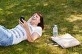 Beautiful woman lying in grass smiling with smart phone Royalty Free Stock Photo