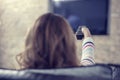 Beautiful woman lying on a sofa with remote control and watching television Royalty Free Stock Photo