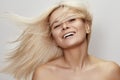 Beautiful woman with magnificent blond hair. Happy model face with windswept flying hair. Shiny long health hairstyle Royalty Free Stock Photo