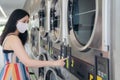 Beautiful woman with mask doing laundry at laundromat shop