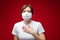 Beautiful woman with medical mask is sick coughs and sneezes, picture isolated on red background