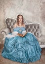 Beautiful woman in medieval dress with book on the sofa Royalty Free Stock Photo