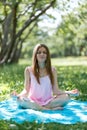 Woman meditating on green grass at the park sitting in lotus position. Fitness girl relaxing in yoga pose after exercises Royalty Free Stock Photo