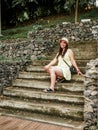 beautiful woman in the middle of a humid park colombian, sitting on a staircase, looking to her left Royalty Free Stock Photo