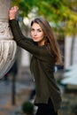 Beautiful woman model dressed in a warm green cardigan posing outside in a city park