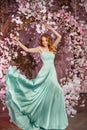 Beautiful woman model in a mint-colored dress on a flowered spring background. Beauty girl with a stunning makeup and hairstyle Royalty Free Stock Photo