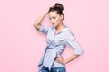 Beautiful woman model posing in jeans and shirt in the studio at pink background. Caucasian, elegance.