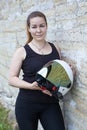 Beautiful woman motorcyclist posing with white open face helmet near stone wall