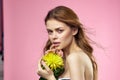 Beautiful woman naked shoulders yellow flower charm cosmetics pink background