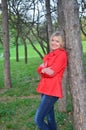 Beautiful woman near the tree in the red jacket