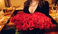 Beautiful woman neckline holding in hand a red rose.