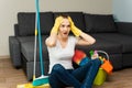 A beautiful woman next to cleaning products and equipment is sitting on the floor and screaming, holding on to her head. A young Royalty Free Stock Photo