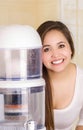 Beautiful woman next to the filter system of water purifier on a kitchen background