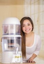 Beautiful woman next to the filter system of water purifier on a kitchen background