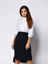 Beautiful woman office manager posing in a new casual white blouse and classic straight dark skirt