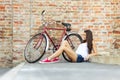 Beautiful woman with old bike in front of a brick wall Royalty Free Stock Photo