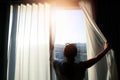 Beautiful woman is opening the curtain at the window in the morning