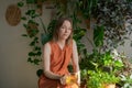 Beautiful woman in orange clothes takes care Ficus blossoms against backdrop