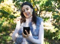 Beautiful woman outdoors, has a wireless earphones in her ears. Hand phone Royalty Free Stock Photo