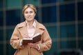 A beautiful woman outside an office building makes a note in a notebook. Royalty Free Stock Photo