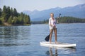 Beautiful woman paddle boarding on scenic mountain lake Royalty Free Stock Photo