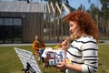 Beautiful woman painting picture on sunny day