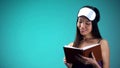 Beautiful woman in pajamas reading book before sleeping, relaxing bedtime ritual