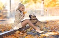 Beautiful woman with perfect legs sitting in the autumn park with a French bulldog dog Royalty Free Stock Photo