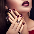 Beautiful woman with perfect make-up and burgundy and golden manicure wearing jewellery Royalty Free Stock Photo