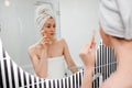 Beautiful woman with perfect skin wearing white towel after shower, making face massage using a jade face roller with natural Royalty Free Stock Photo