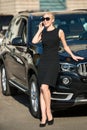 Beautiful woman with phone leaned on car