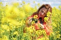 Beautiful woman photographer smiling and looking at her camera, inside a yellow rapeseed field Royalty Free Stock Photo