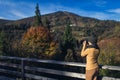 Beautiful woman photographs nature on the mountain in autumn