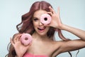 Beautiful woman with pink hair, beautiful makeup with donuts in her hands posing in the studio.