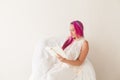 Beautiful woman with pink hair reading a book in a white room Royalty Free Stock Photo